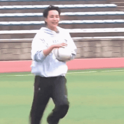 A Man Is Running On A Field With A Soccer Ball In His Hand . GIF