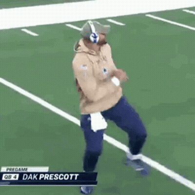 A Man Is Running On A Football Field Wearing Headphones And A Hat . GIF