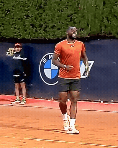 A Man Is Running On A Tennis Court In Front Of A Bmw Sign GIF