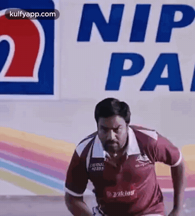 A Man Is Running On A Track In Front Of A Sign That Says Nip Pa . GIF