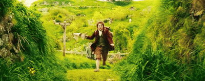 A Man Is Running Through A Grassy Field With A Backpack On His Back . GIF