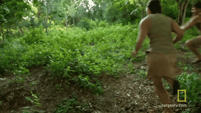 A Man Is Running Through A Lush Green Forest With A National Geographic Logo On The Bottom GIF