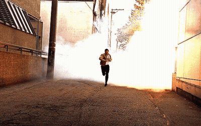 A Man Is Running Through A Smokey Alleyway GIF