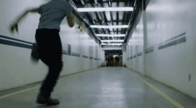 A Man Is Running Through A Tunnel With A Yellow Line On The Floor GIF