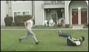 A Man Is Running While Another Man Is Laying On The Ground . GIF