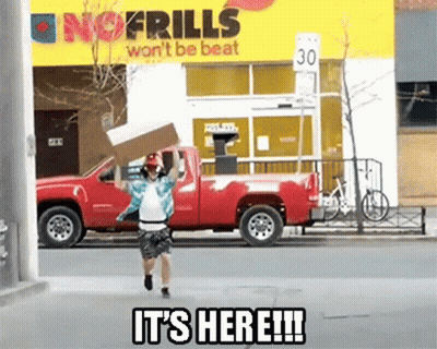 A Man Is Running With A Cardboard Box In Front Of A No Frills Sign GIF