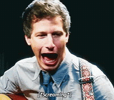 A Man Is Screaming While Holding A Guitar And Wearing A Tie . GIF