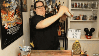 A Man Is Shaking A Drink In Front Of A Sign That Says " The Tambur Lapu " GIF