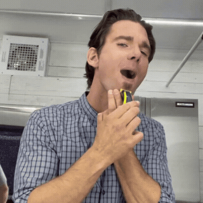 A Man Is Shaving His Face In Front Of A Maximum Fridge GIF