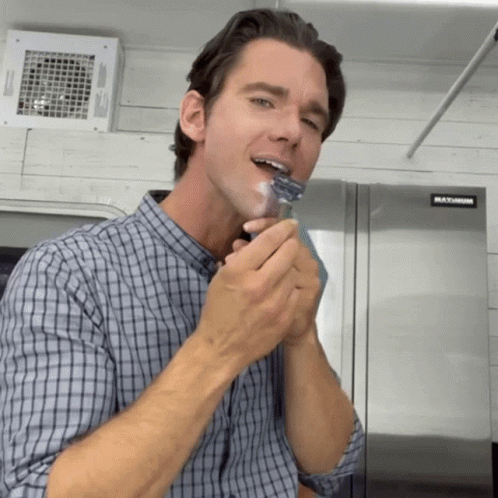 A Man Is Shaving His Face In Front Of A Refrigerator That Says Maximum GIF