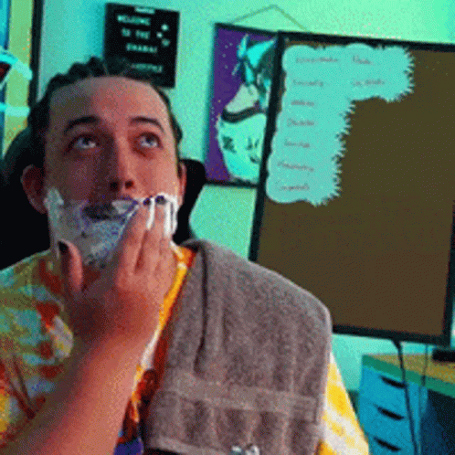 A Man Is Shaving His Face In Front Of A Sign That Says " Welcome To The Channel " GIF