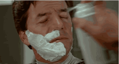 A Man Is Shaving His Face With A Razor And Shaving Cream On His Face . GIF