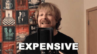 A Man Is Singing Into A Microphone And The Word Expensive Is On The Screen Behind Him GIF