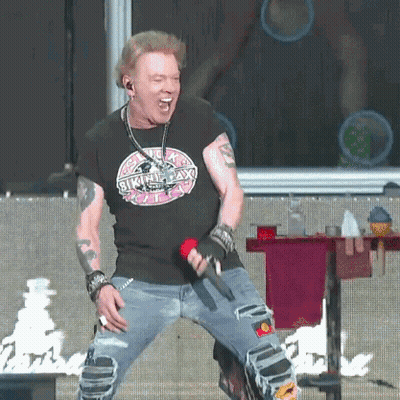 A Man Is Singing Into A Microphone And Wearing A Shirt That Says Skinny Lax GIF