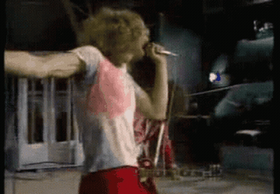 A Man Is Singing Into A Microphone In A Dark Room GIF