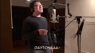 A Man Is Singing Into A Microphone In A Recording Studio And The Words Daytonaaa Are Above Him . GIF