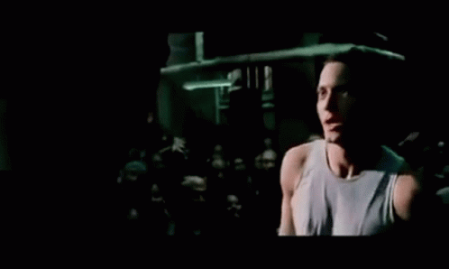 A Man Is Singing Into A Microphone In Front Of A Crowd At A Concert . GIF