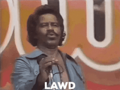 A Man Is Singing Into A Microphone In Front Of A Large Sign . GIF