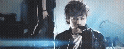 A Man Is Singing Into A Microphone On A Stage In Front Of A Crowd . GIF