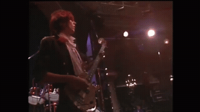 A Man Is Singing Into A Microphone On A Stage In Front Of A Crowd Of People . GIF