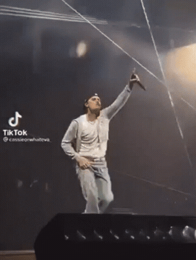 A Man Is Singing Into A Microphone On A Stage With A Tiktok Watermark GIF