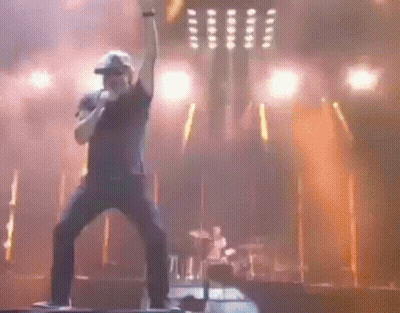 A Man Is Singing Into A Microphone On Stage GIF