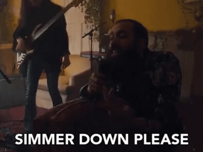 A Man Is Singing Into A Microphone While Another Man Plays A Guitar Behind Him . GIF