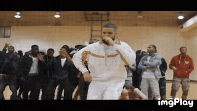 A Man Is Singing Into A Microphone While Dancing In Front Of A Crowd . GIF