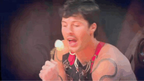 A Man Is Singing Into A Microphone While Holding An Ice Cream Cone .. GIF
