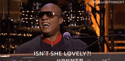 A Man Is Singing Into A Microphone While Sitting At A Keyboard . GIF