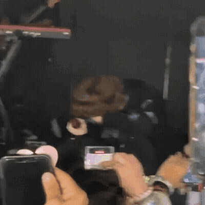 A Man Is Singing Into A Microphone While Someone Takes A Picture GIF