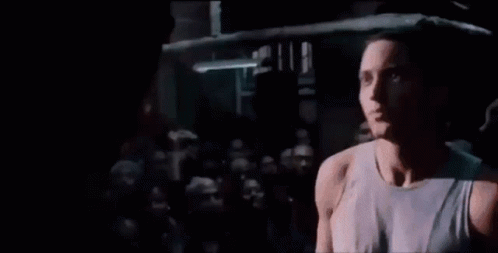 A Man Is Singing Into A Microphone While Standing In A Boxing Ring . GIF