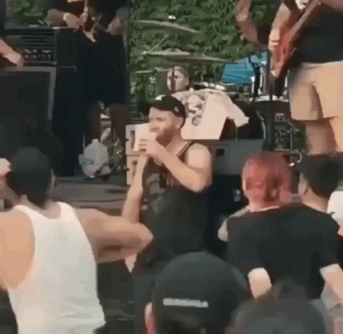 A Man Is Singing Into A Microphone While Standing In Front Of A Crowd . GIF