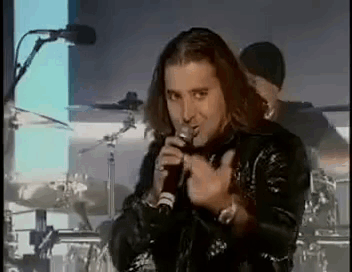 A Man Is Singing Into A Microphone While Standing On A Stage . GIF