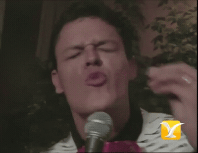 A Man Is Singing Into A Microphone With A Bird On It GIF