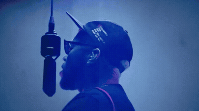 A Man Is Singing Into A Microphone With A Hat That Says ' I Love You ' On It GIF