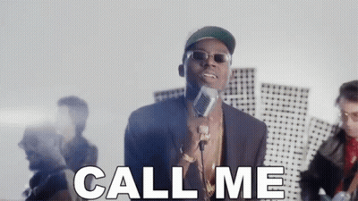 A Man Is Singing Into A Microphone With The Words Call Me Behind Him . GIF