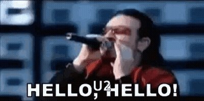 A Man Is Singing Into A Microphone With The Words `` Hello , Hello ! '' Written On It . GIF
