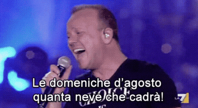 A Man Is Singing Into A Microphone With The Words Le Domeniche D' Agosto Quanta Neve Che-Cadra GIF