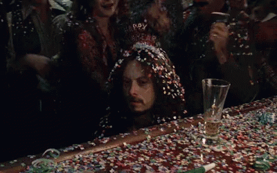 A Man Is Sitting At A Bar Covered In Confetti And A Martini Glass . GIF