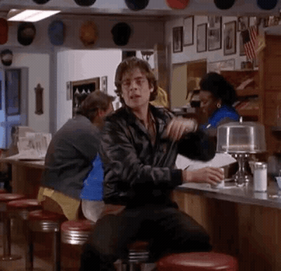 A Man Is Sitting At A Counter In A Diner Holding A Cup Of Coffee . GIF