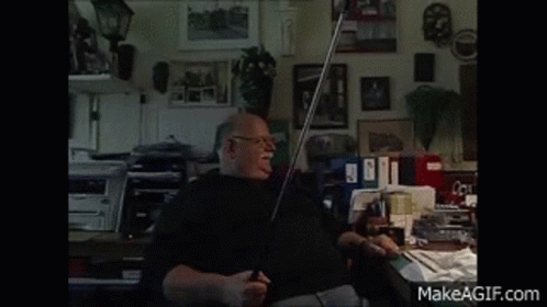 A Man Is Sitting At A Desk In A Room With A Makeagif.com Watermark In The Corner GIF