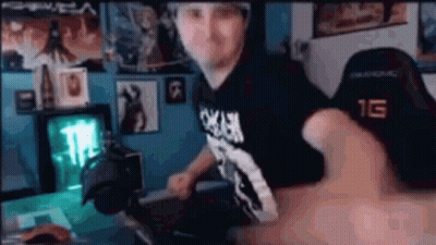 A Man Is Sitting At A Desk In Front Of A Computer In A Room . GIF
