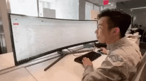 A Man Is Sitting At A Desk In Front Of A Computer Monitor And Keyboard . GIF