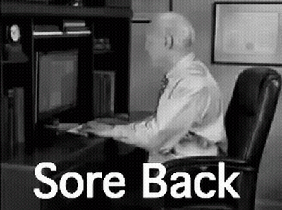A Man Is Sitting At A Desk In Front Of A Computer With The Words `` Sore Back '' Written On It . GIF