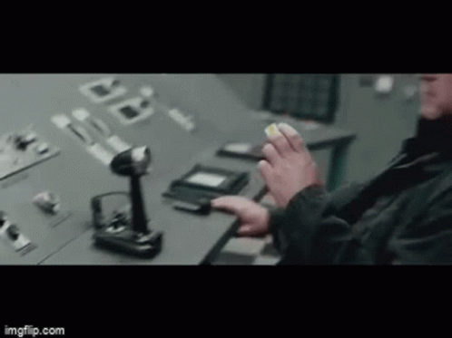 A Man Is Sitting At A Desk In Front Of A Control Panel . GIF
