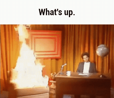 A Man Is Sitting At A Desk In Front Of A Fire And The Words What 'S Up . GIF