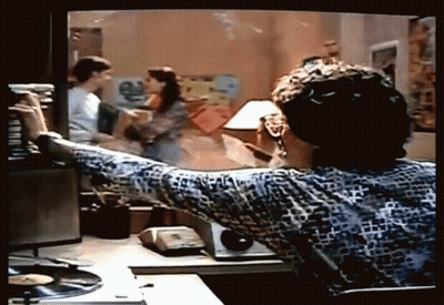 A Man Is Sitting At A Desk Looking At A Tv Screen GIF