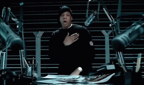A Man Is Sitting At A Desk With A Bunch Of Microphones . GIF