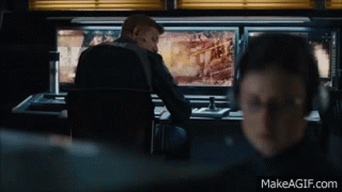 A Man Is Sitting At A Desk With A Computer Monitor In Front Of Him And The Website Makeagif.com Is Below Him GIF